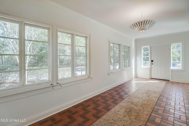 entryway with brick floor, baseboards, and crown molding