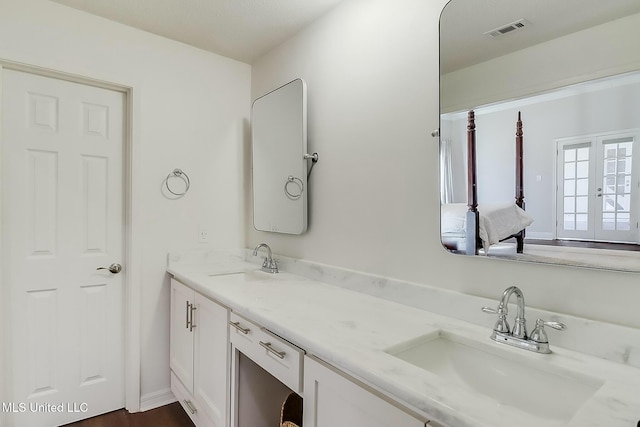 bathroom featuring double vanity, visible vents, a sink, and french doors