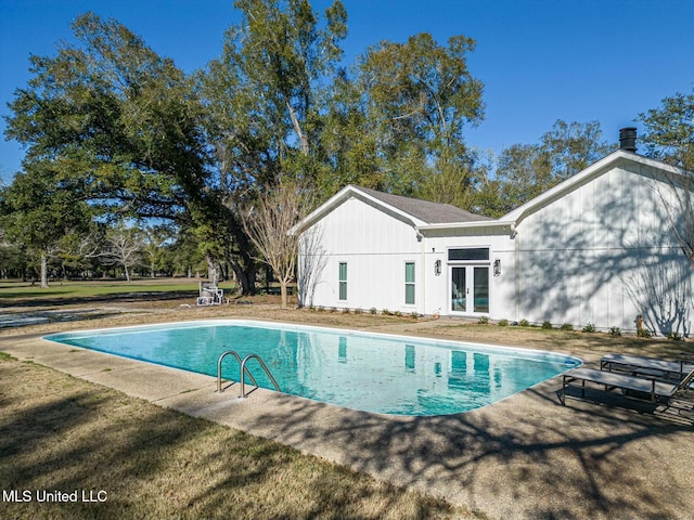 outdoor pool with french doors and a lawn