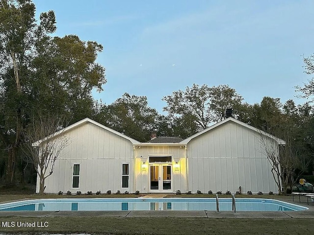 back of property with french doors and an outdoor pool