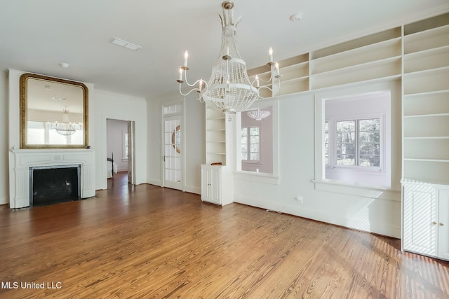 unfurnished living room featuring an inviting chandelier, a fireplace, visible vents, and wood finished floors