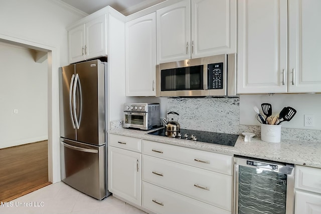 kitchen with light stone counters, a toaster, appliances with stainless steel finishes, white cabinetry, and beverage cooler