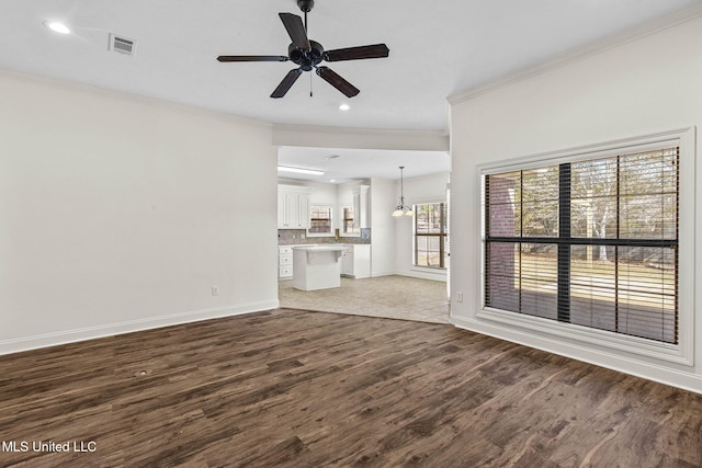 unfurnished living room with hardwood / wood-style flooring, ceiling fan with notable chandelier, and ornamental molding