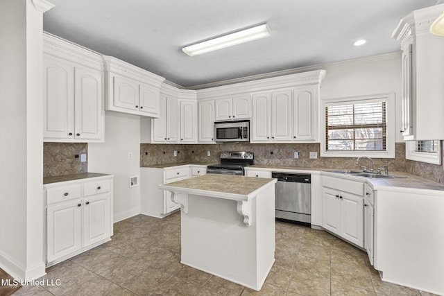 kitchen with white cabinets, appliances with stainless steel finishes, a kitchen island, and sink