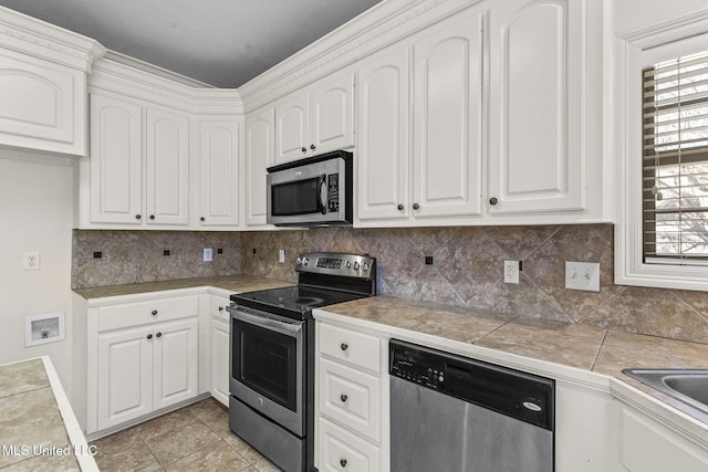 kitchen with tile countertops, decorative backsplash, white cabinetry, and appliances with stainless steel finishes