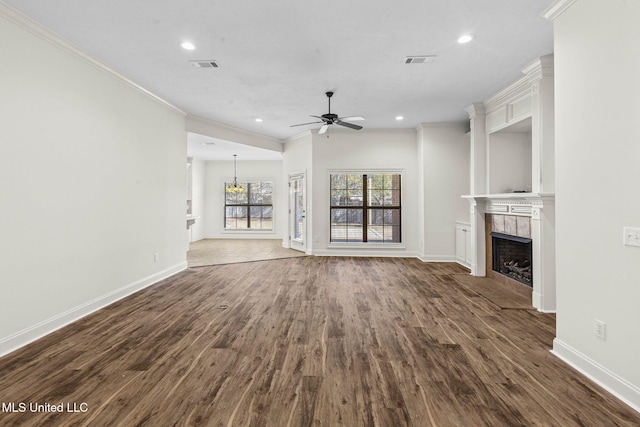 unfurnished living room with ceiling fan, ornamental molding, dark wood-type flooring, and a tiled fireplace