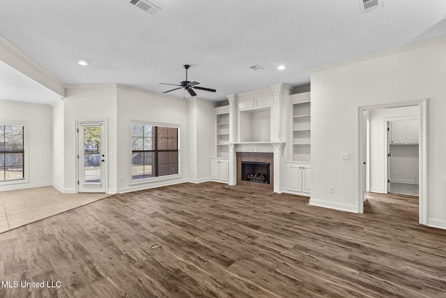 unfurnished living room featuring ceiling fan, dark hardwood / wood-style floors, ornamental molding, and built in features