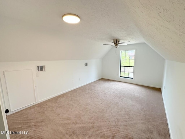 additional living space featuring vaulted ceiling, visible vents, carpet floors, and a textured ceiling