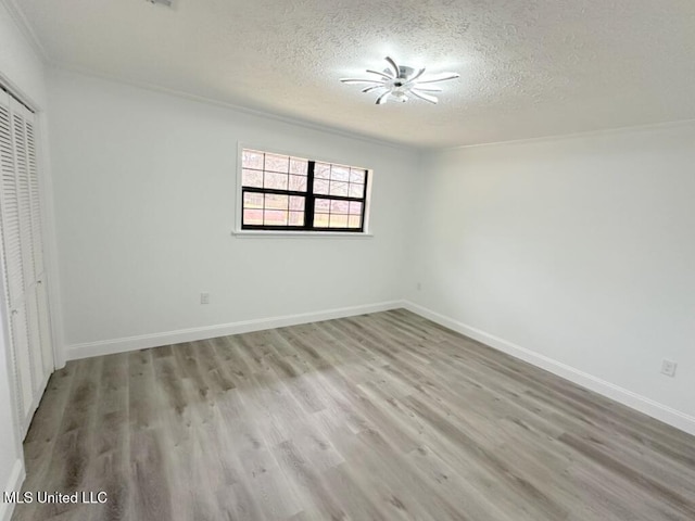 unfurnished bedroom with a closet, a textured ceiling, baseboards, and wood finished floors