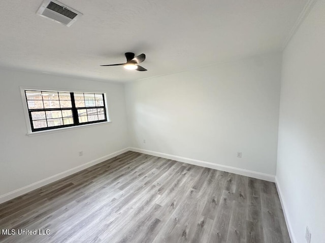 spare room featuring visible vents, baseboards, wood finished floors, and a ceiling fan