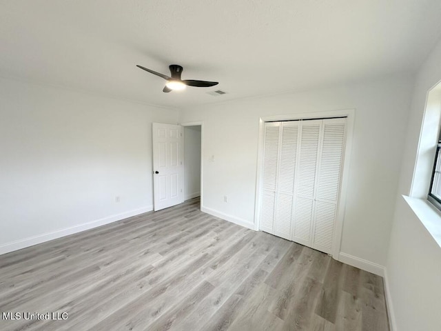 unfurnished bedroom featuring visible vents, ceiling fan, baseboards, light wood-style floors, and a closet