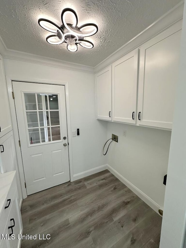 laundry room featuring washer hookup, ornamental molding, a textured ceiling, wood finished floors, and cabinet space