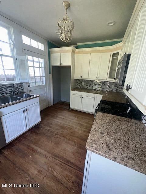 kitchen with sink, backsplash, hanging light fixtures, white cabinets, and dark wood-type flooring