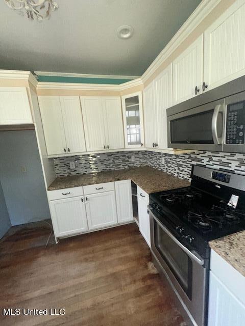 kitchen with tasteful backsplash, dark hardwood / wood-style flooring, appliances with stainless steel finishes, white cabinetry, and dark stone countertops