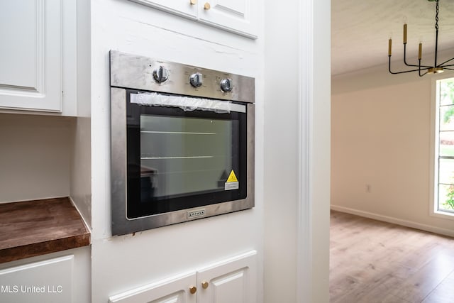 18 Crossgates Dr, Brandon, MS 39042 - detailed view of a chandelier, white cabinets, wood finished floors, stainless steel oven, and baseboards