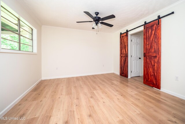 18 Crossgates Dr, Brandon, MS 39042 - spare room featuring a ceiling fan, a barn door, light wood finished floors, crown molding, and baseboards