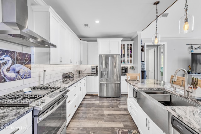 kitchen featuring appliances with stainless steel finishes, wall chimney range hood, white cabinets, and light stone counters