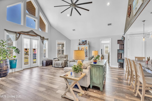 living room with high vaulted ceiling, french doors, a healthy amount of sunlight, and light hardwood / wood-style flooring