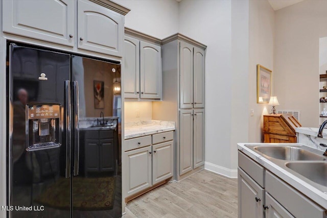 kitchen featuring gray cabinets, black refrigerator with ice dispenser, sink, and light hardwood / wood-style floors