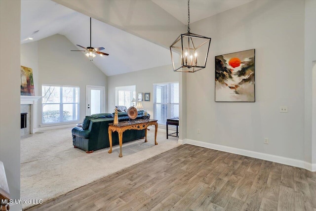 living room featuring wood-type flooring, ceiling fan with notable chandelier, and high vaulted ceiling