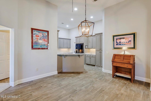 kitchen with gray cabinets, black fridge, pendant lighting, and light hardwood / wood-style floors