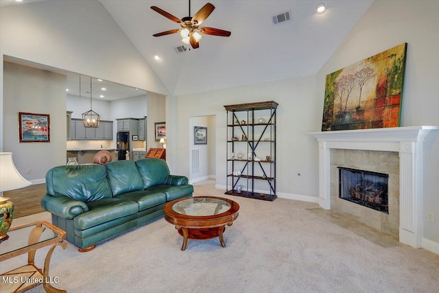 living room featuring ceiling fan, a fireplace, high vaulted ceiling, and light carpet