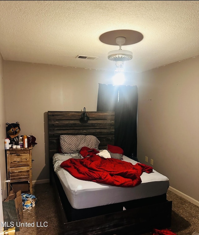 carpeted bedroom with a textured ceiling, visible vents, and baseboards