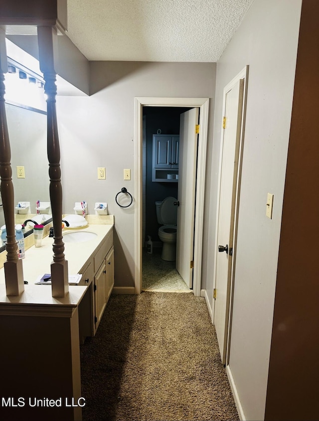 bathroom featuring baseboards, toilet, a textured ceiling, and vanity