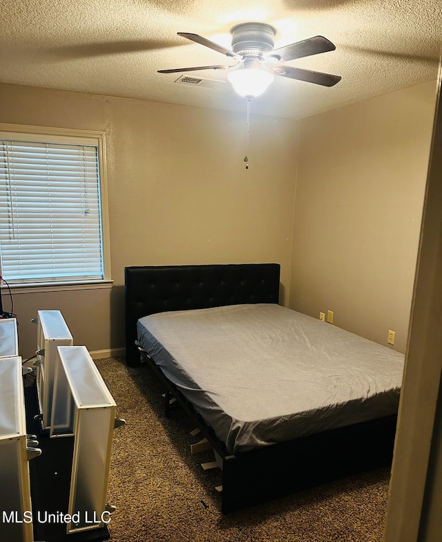 bedroom featuring carpet floors, visible vents, ceiling fan, and a textured ceiling