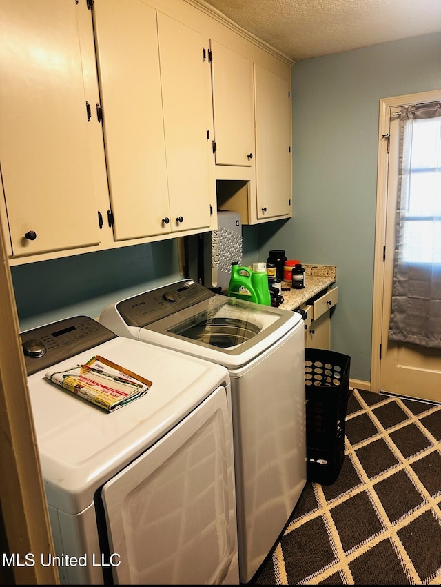 washroom featuring a textured ceiling, independent washer and dryer, cabinet space, and baseboards