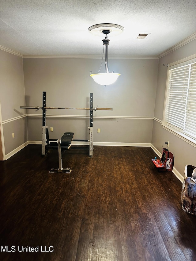 exercise room featuring visible vents, a textured ceiling, baseboards, and wood finished floors