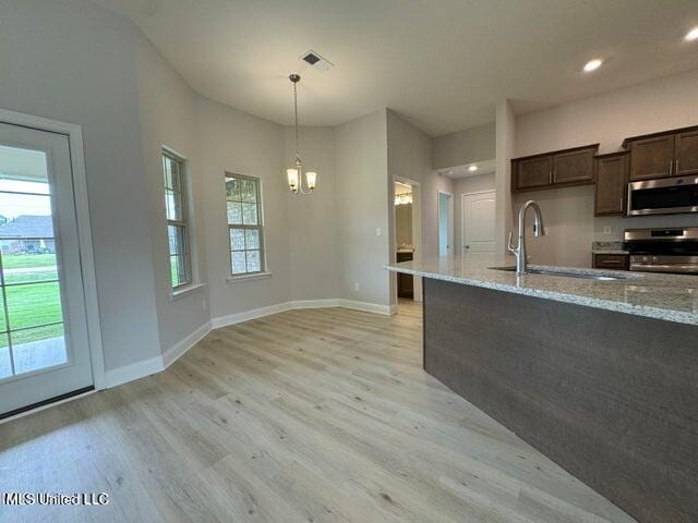 kitchen featuring light stone countertops, stainless steel appliances, an inviting chandelier, and sink