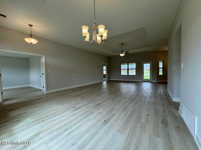 empty room featuring ceiling fan with notable chandelier and light hardwood / wood-style floors