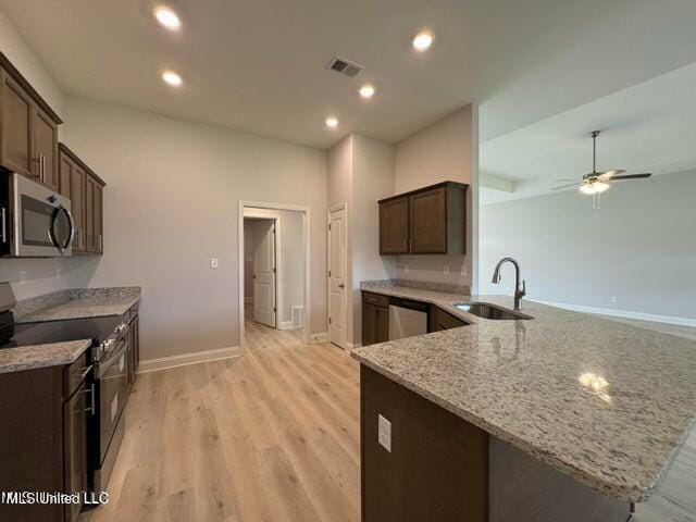 kitchen with sink, light hardwood / wood-style flooring, light stone counters, kitchen peninsula, and stainless steel appliances