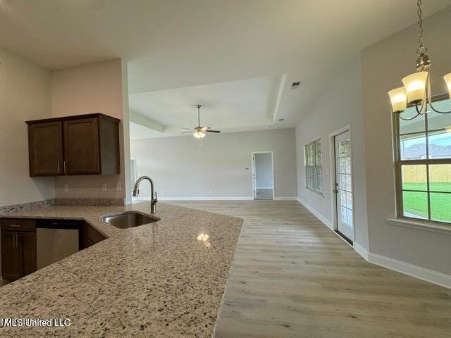 kitchen with sink, light stone counters, light hardwood / wood-style flooring, stainless steel dishwasher, and ceiling fan with notable chandelier