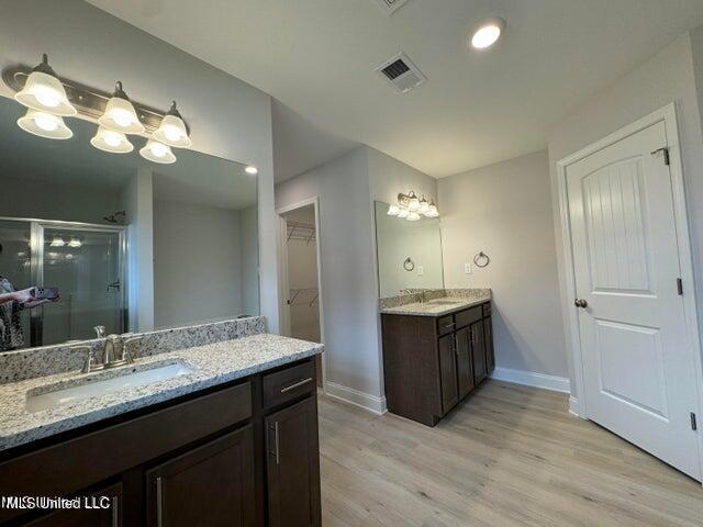 bathroom with wood-type flooring, vanity, and a shower with door