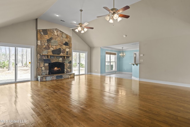 unfurnished living room featuring visible vents, ceiling fan with notable chandelier, a fireplace, and wood finished floors