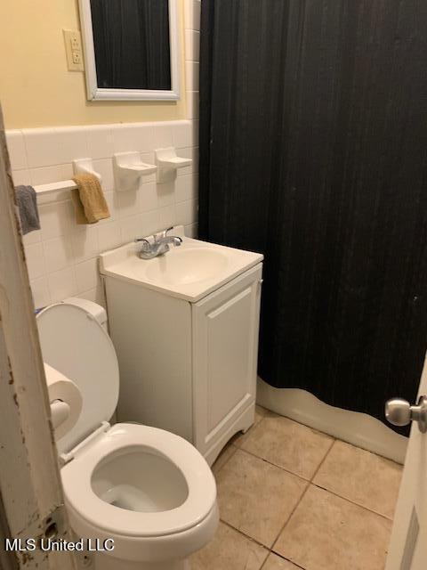 1509 Eastwood Rd, Natchez, MS 39120 - bathroom featuring toilet, a shower with shower curtain, vanity, tile patterned flooring, and wainscoting