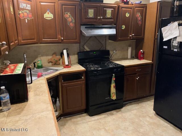 1509 Eastwood Rd, Natchez, MS 39120 - kitchen with black appliances, under cabinet range hood, light countertops, a sink, and light tile patterned floors
