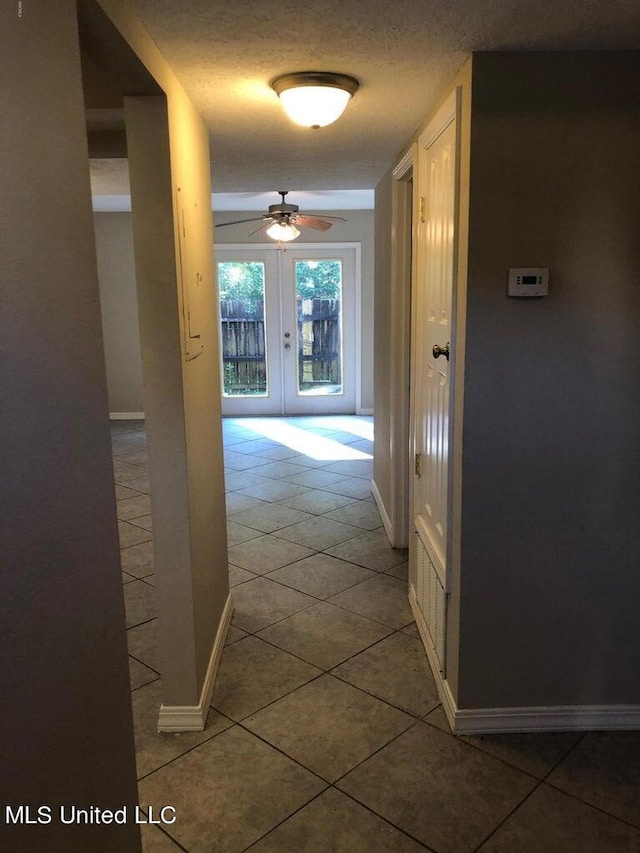 hallway featuring french doors, a textured ceiling, and tile patterned floors