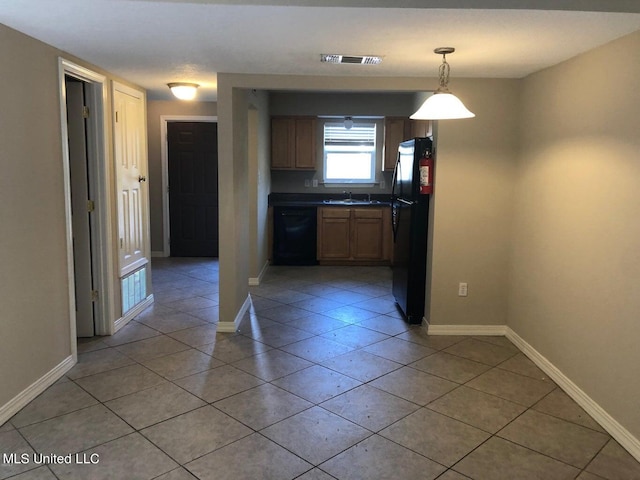 kitchen featuring sink, black appliances, light tile patterned flooring, and hanging light fixtures