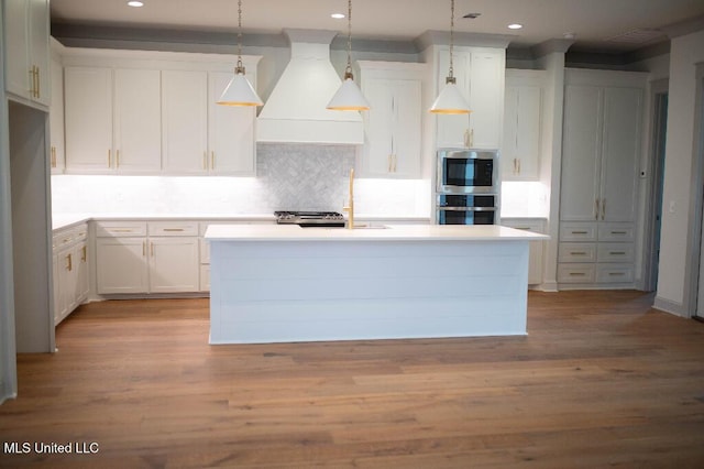256 Arbor Trl, Brandon, MS 39047 - kitchen with premium range hood, an island with sink, decorative backsplash, wood finished floors, and hanging light fixtures