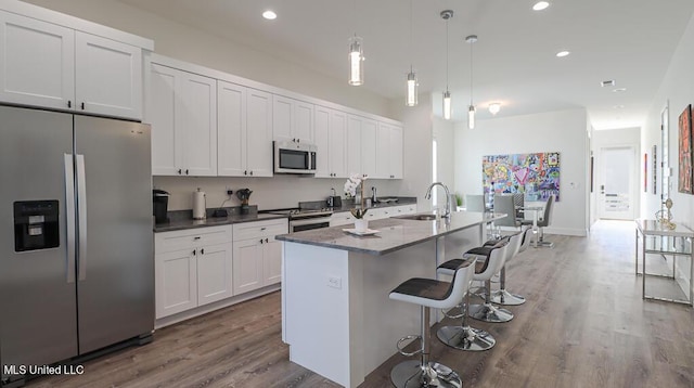 kitchen featuring sink, an island with sink, pendant lighting, white cabinets, and appliances with stainless steel finishes