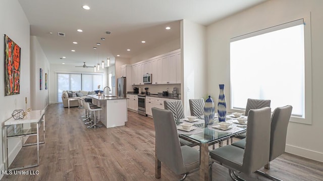 dining space featuring light hardwood / wood-style flooring, ceiling fan, and sink