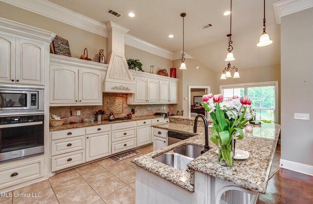 kitchen with visible vents, a center island with sink, tasteful backsplash, a sink, and stainless steel appliances