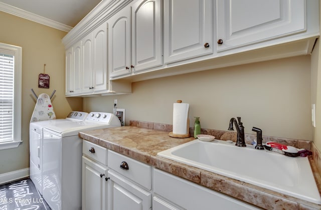 clothes washing area featuring a sink, a wealth of natural light, cabinet space, and washer and dryer
