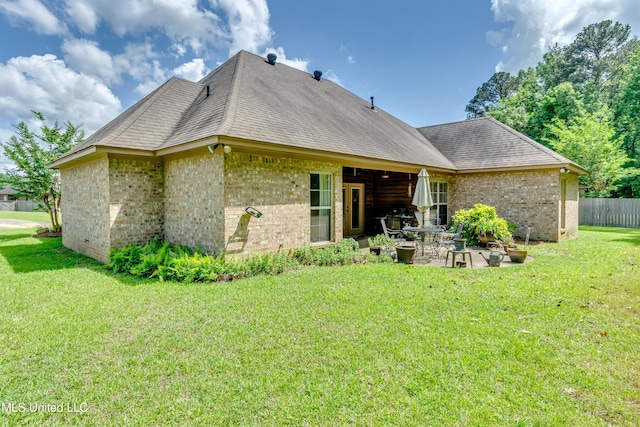 back of property featuring roof with shingles, a patio, a yard, and brick siding