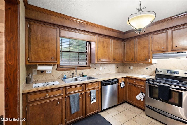 kitchen with stainless steel appliances, under cabinet range hood, a sink, light countertops, and decorative backsplash