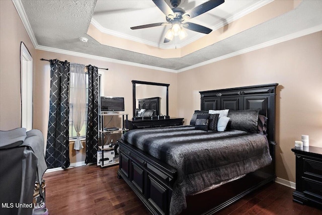 bedroom featuring a tray ceiling, dark wood-style flooring, baseboards, crown molding, and ceiling fan