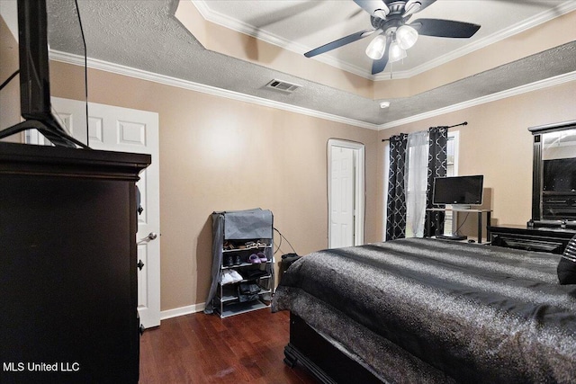 bedroom featuring a tray ceiling, wood finished floors, ornamental molding, a ceiling fan, and baseboards